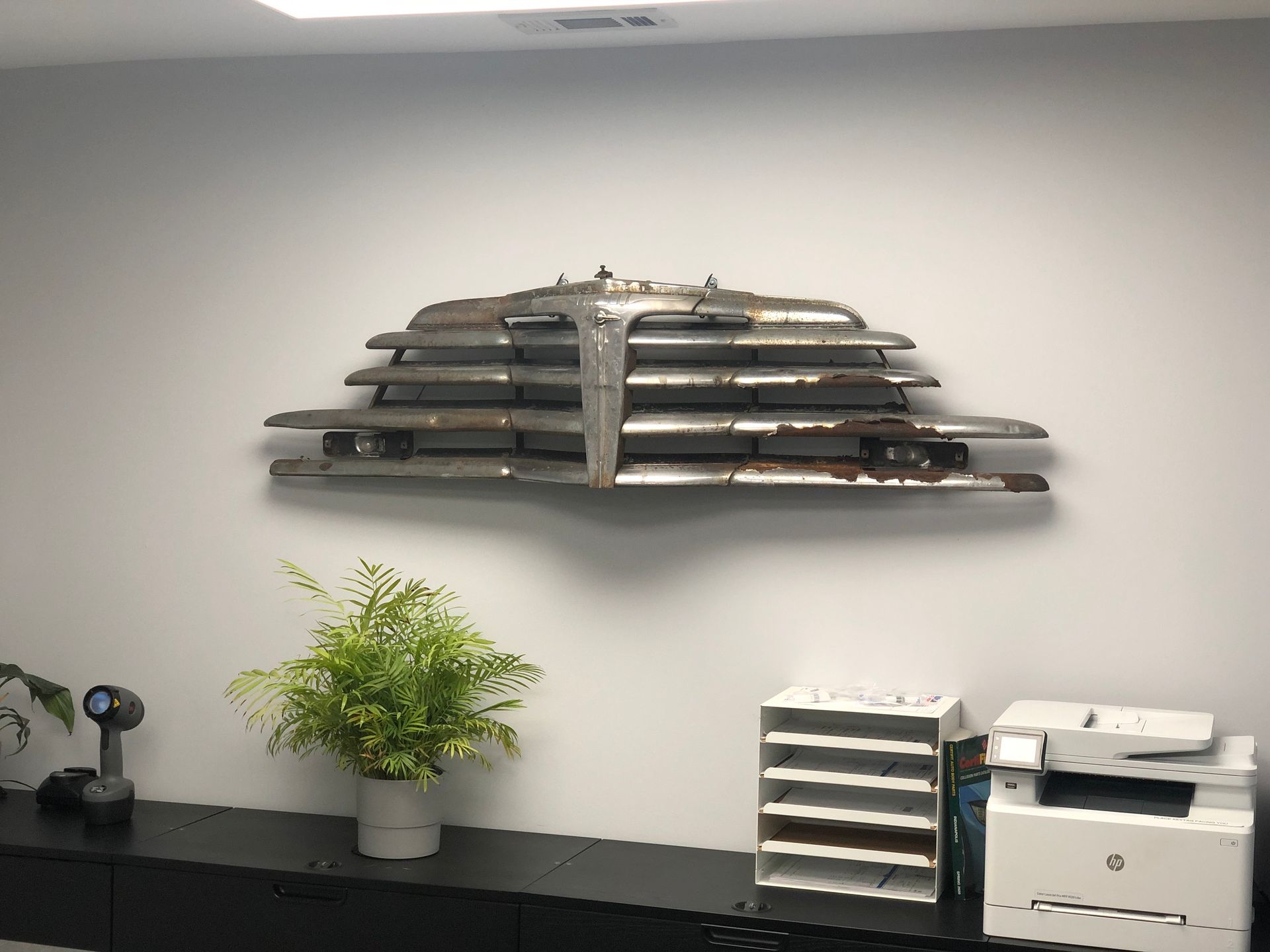 A white wall with a plant and a printer on it