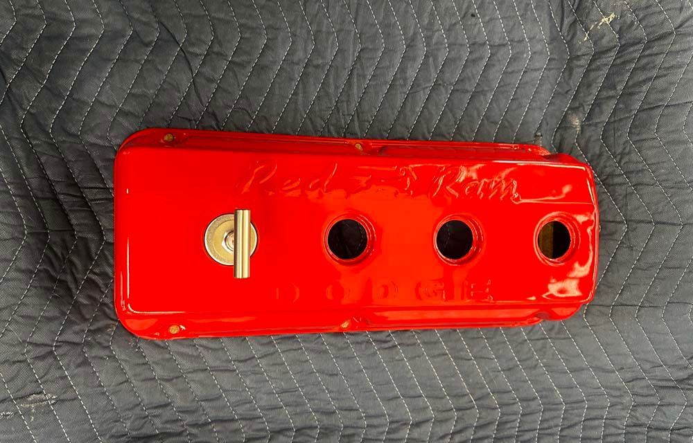 A red valve cover is laying on a gray blanket.