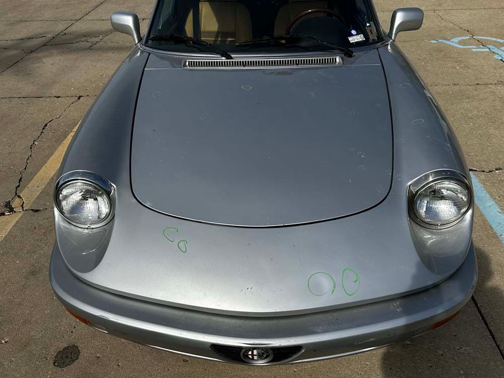 A silver car is parked in a handicapped parking spot.