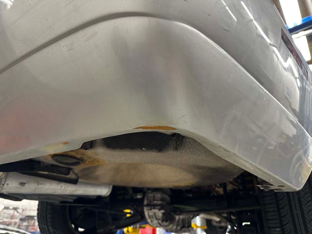 A white car is parked on a lift in a garage.