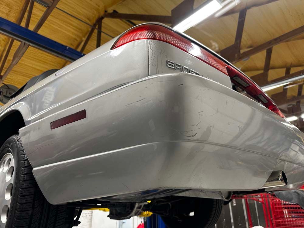 A silver car is sitting on a lift in a garage.