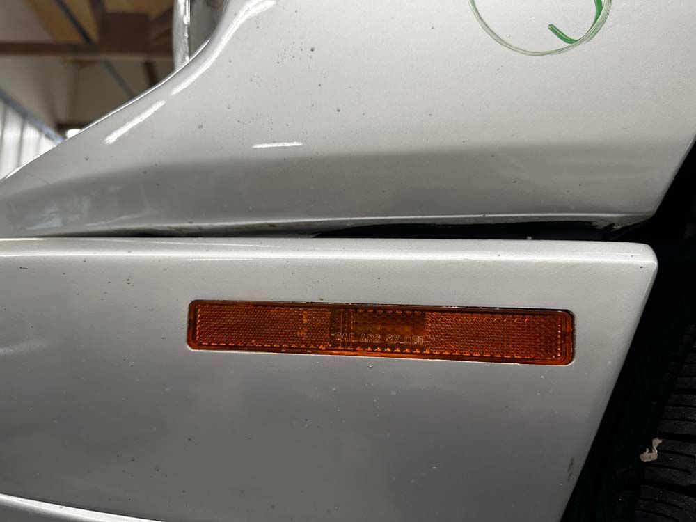 A close up of a side marker light on a silver car.