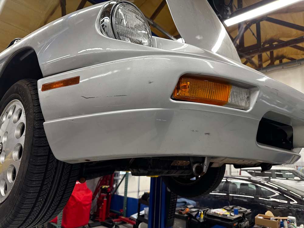 A silver car is sitting on a lift in a garage.