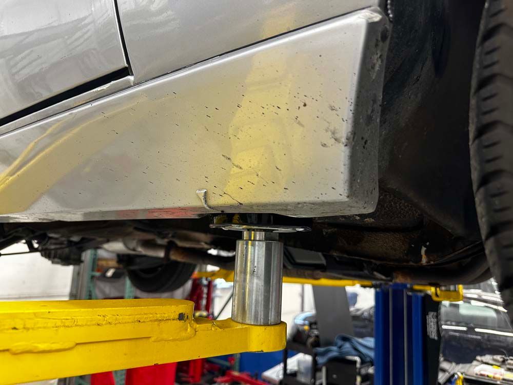 A car is sitting on a yellow lift in a garage