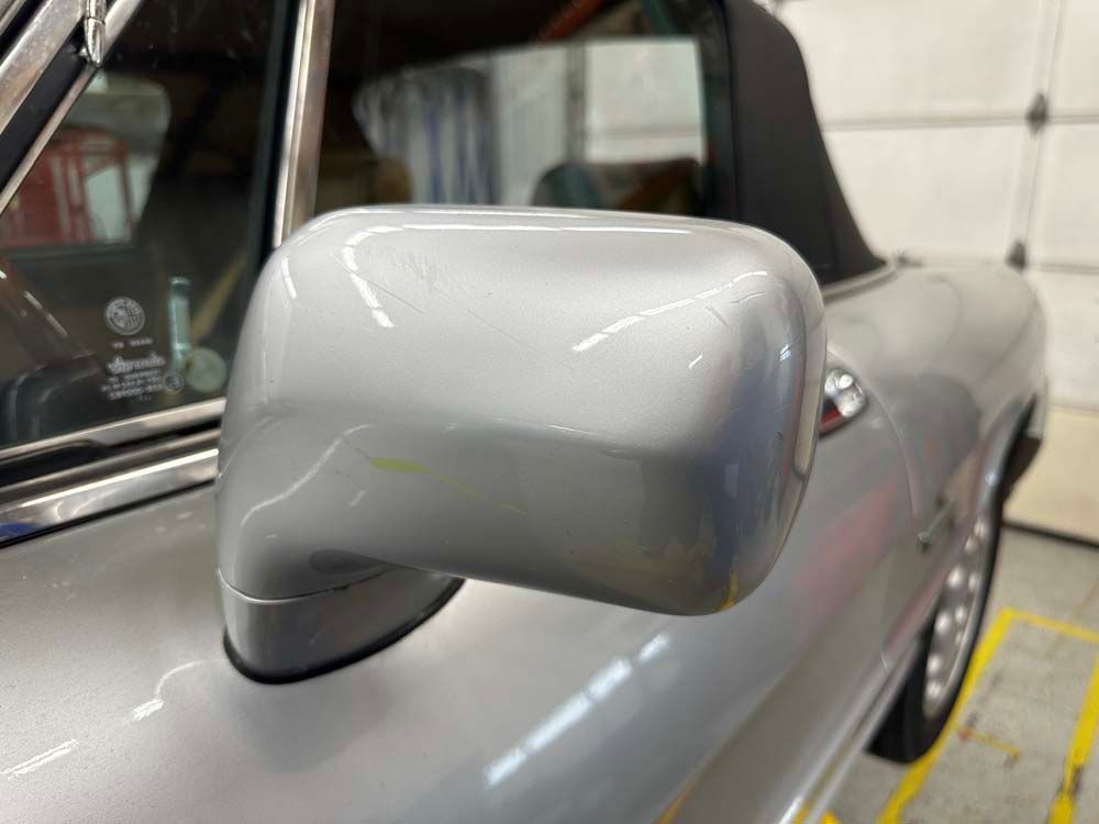 A close up of a side view mirror on a silver car.
