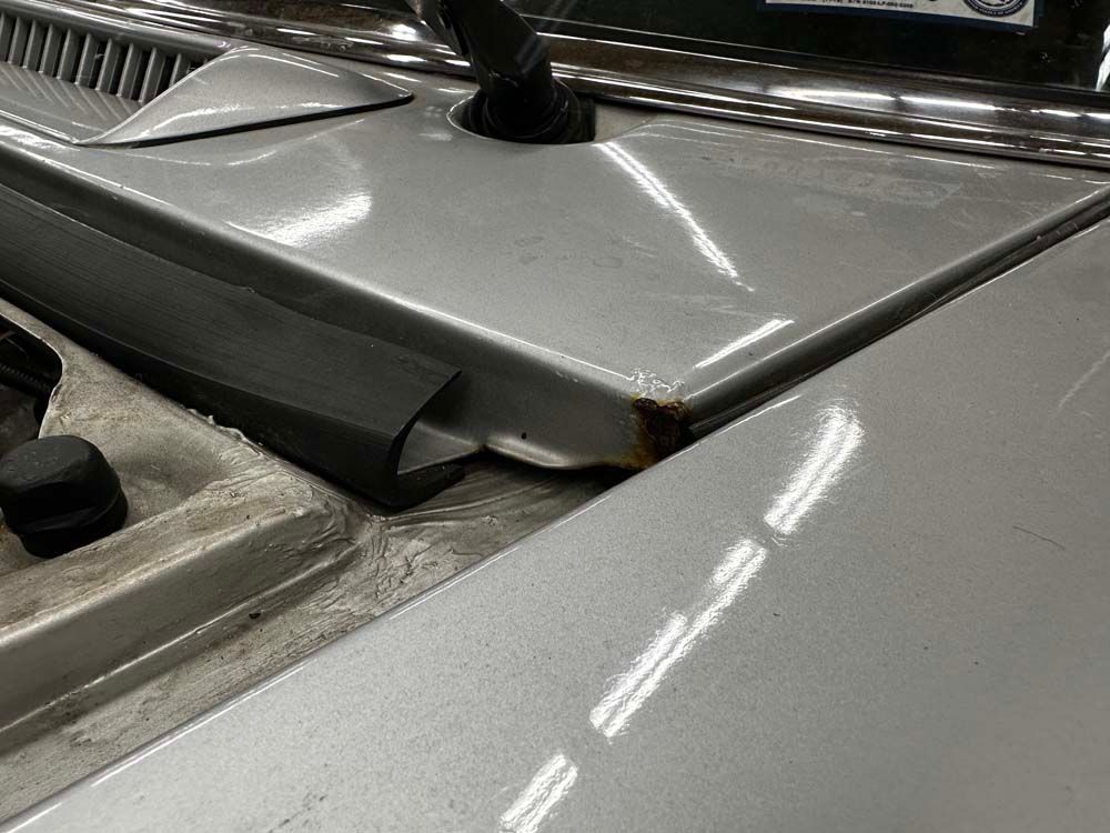 A close up of the hood of a silver car.