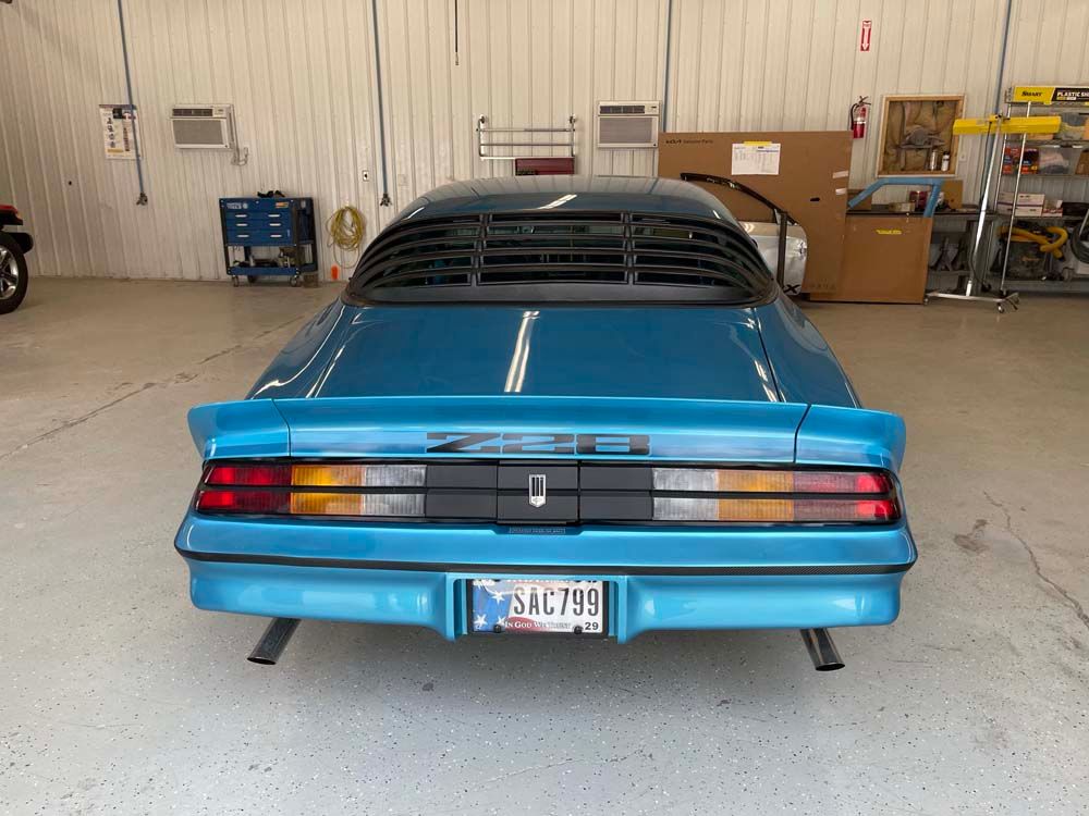 A blue car with a california license plate is parked in a garage.