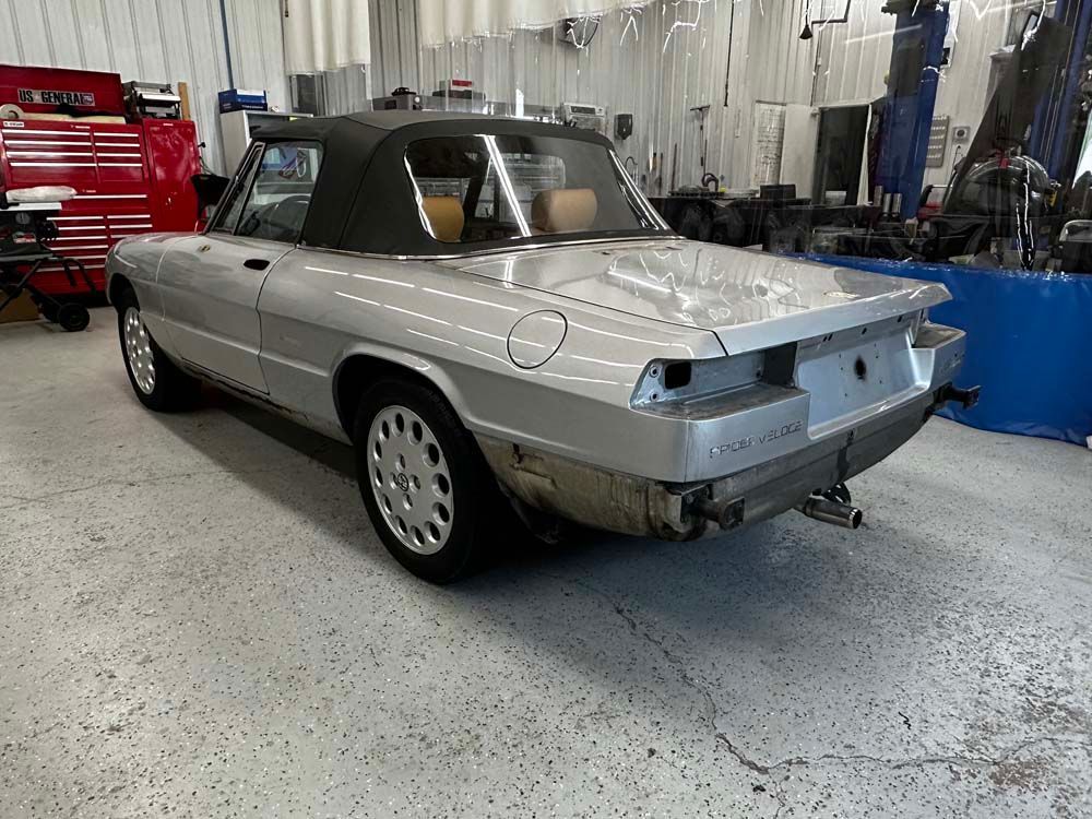 A silver convertible is parked in a garage.