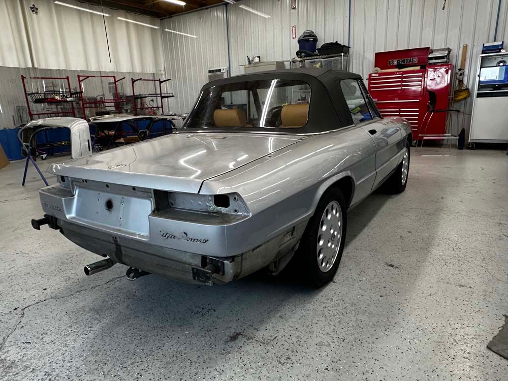 A silver convertible car is parked in a garage.