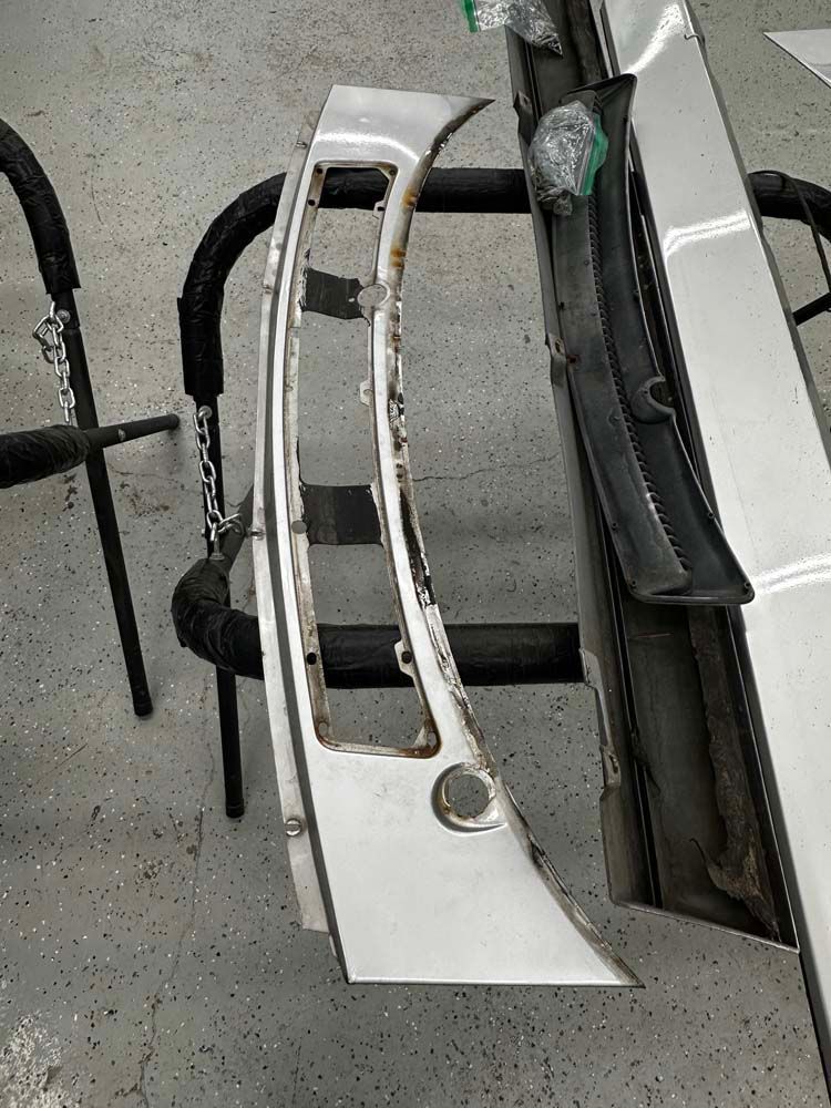 A car bumper is sitting on a rack in a garage.