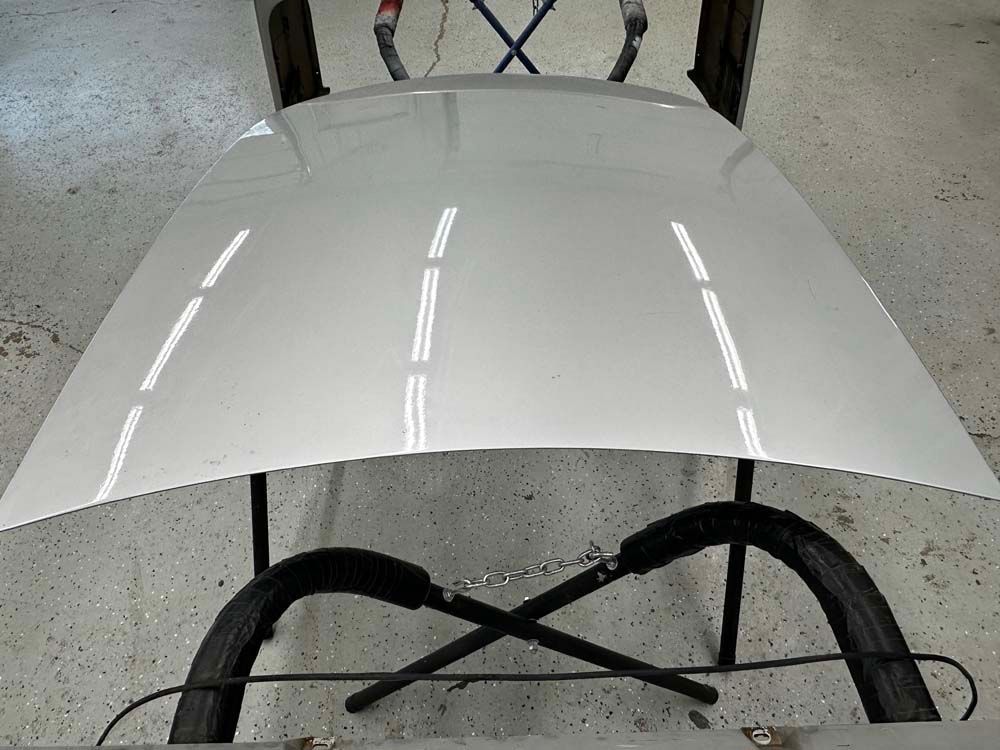 The hood of a car is sitting on a table in a garage.