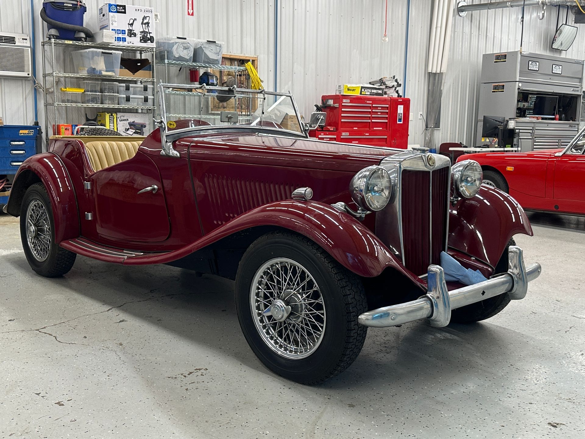 Burgundy classic convertible car parked in a garage.