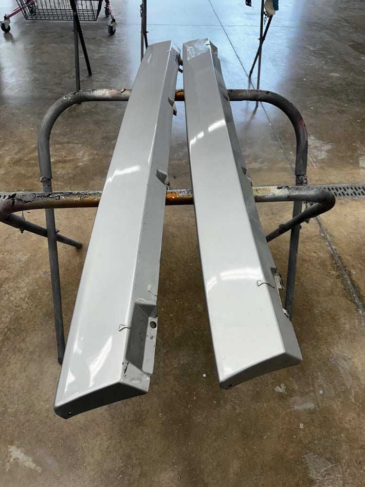 A pair of side skirts are sitting on top of a metal stand.