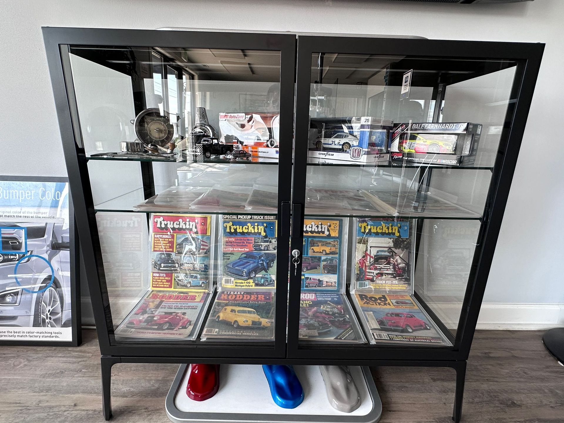 A glass display case filled with magazines and toys in a living room.