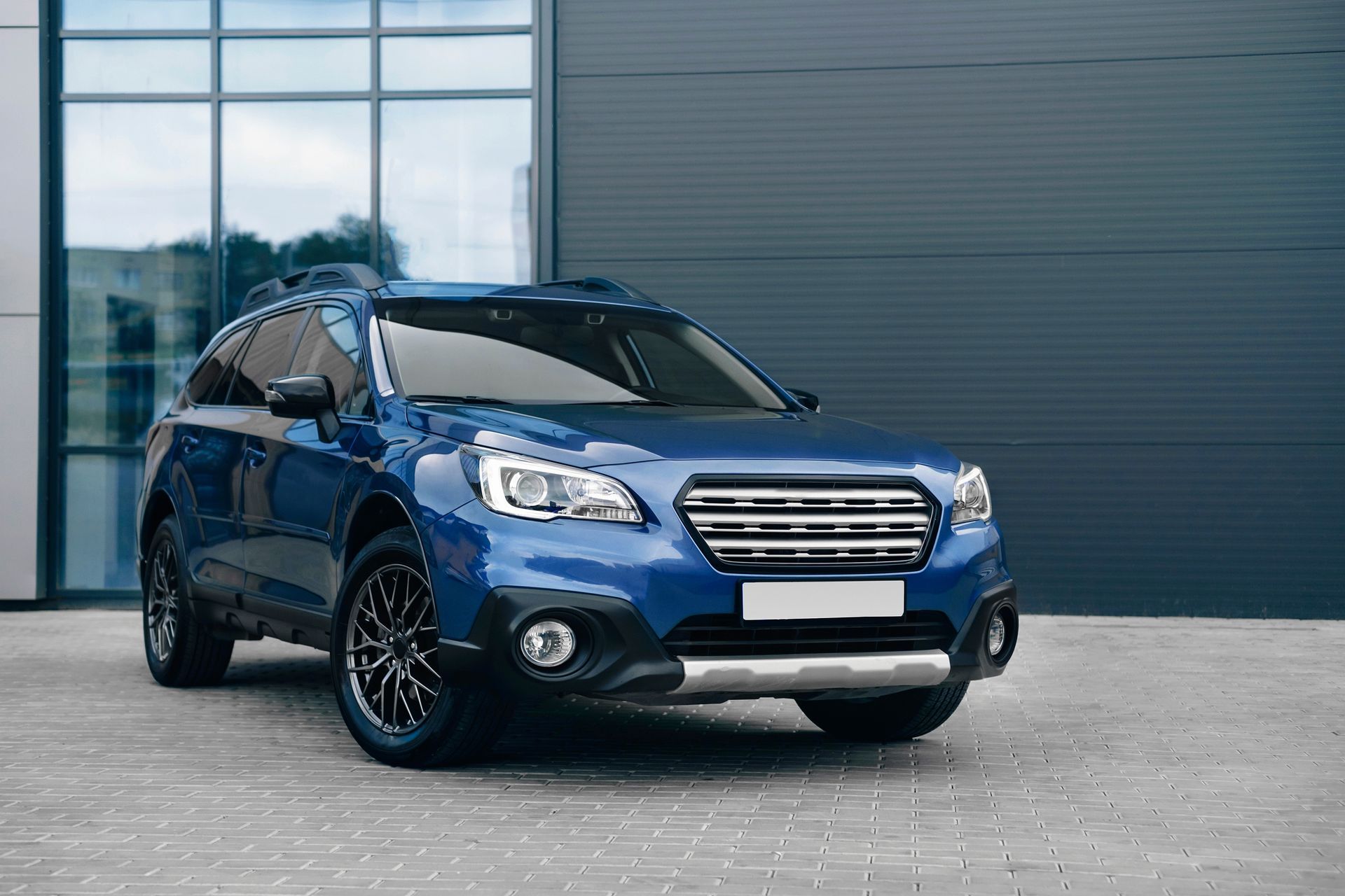 A blue suv is parked in front of a building.