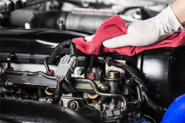 gloved hand wiping engine with pink towel