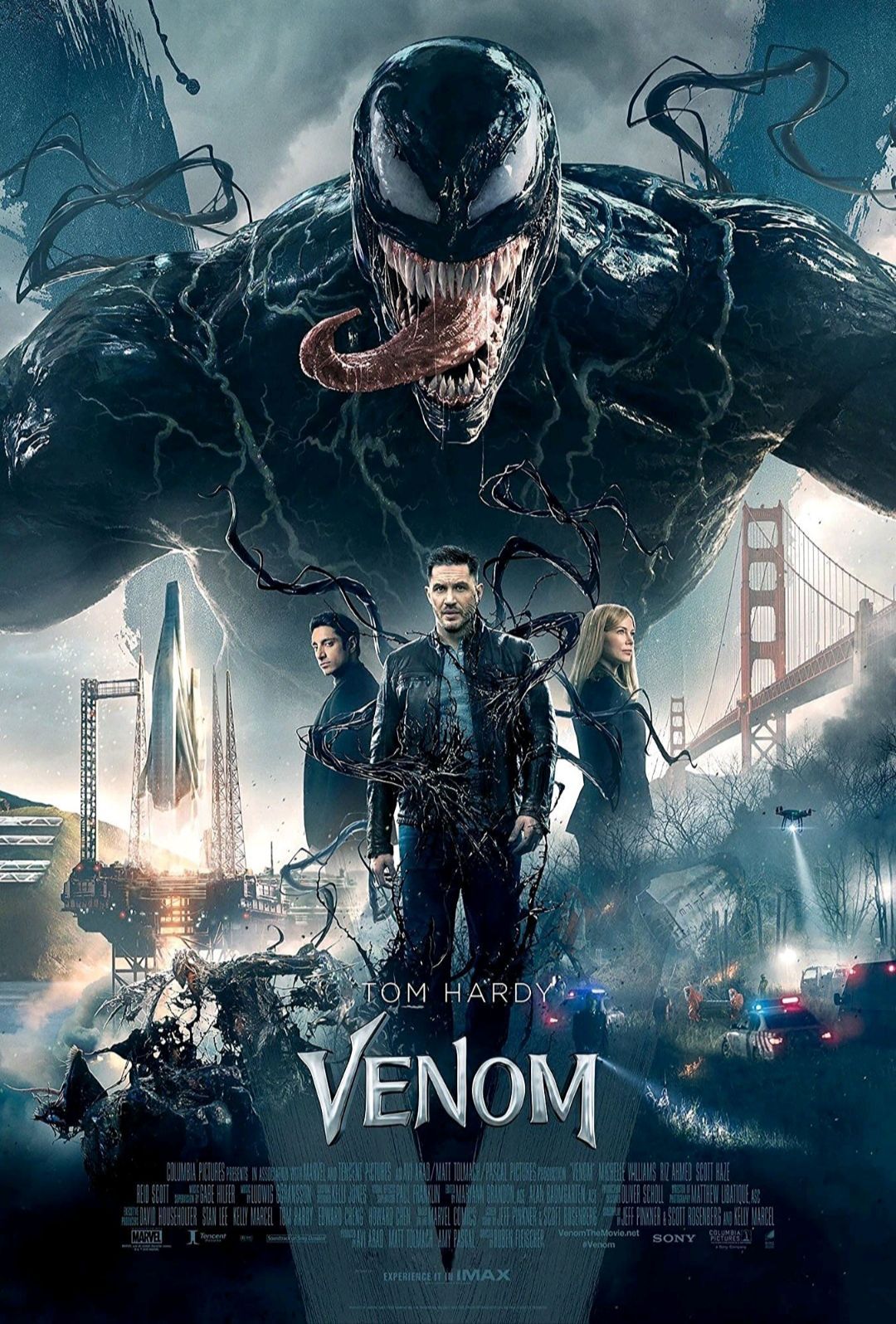 Venom movie poster. Giant black Venom looms behind three people and city.
