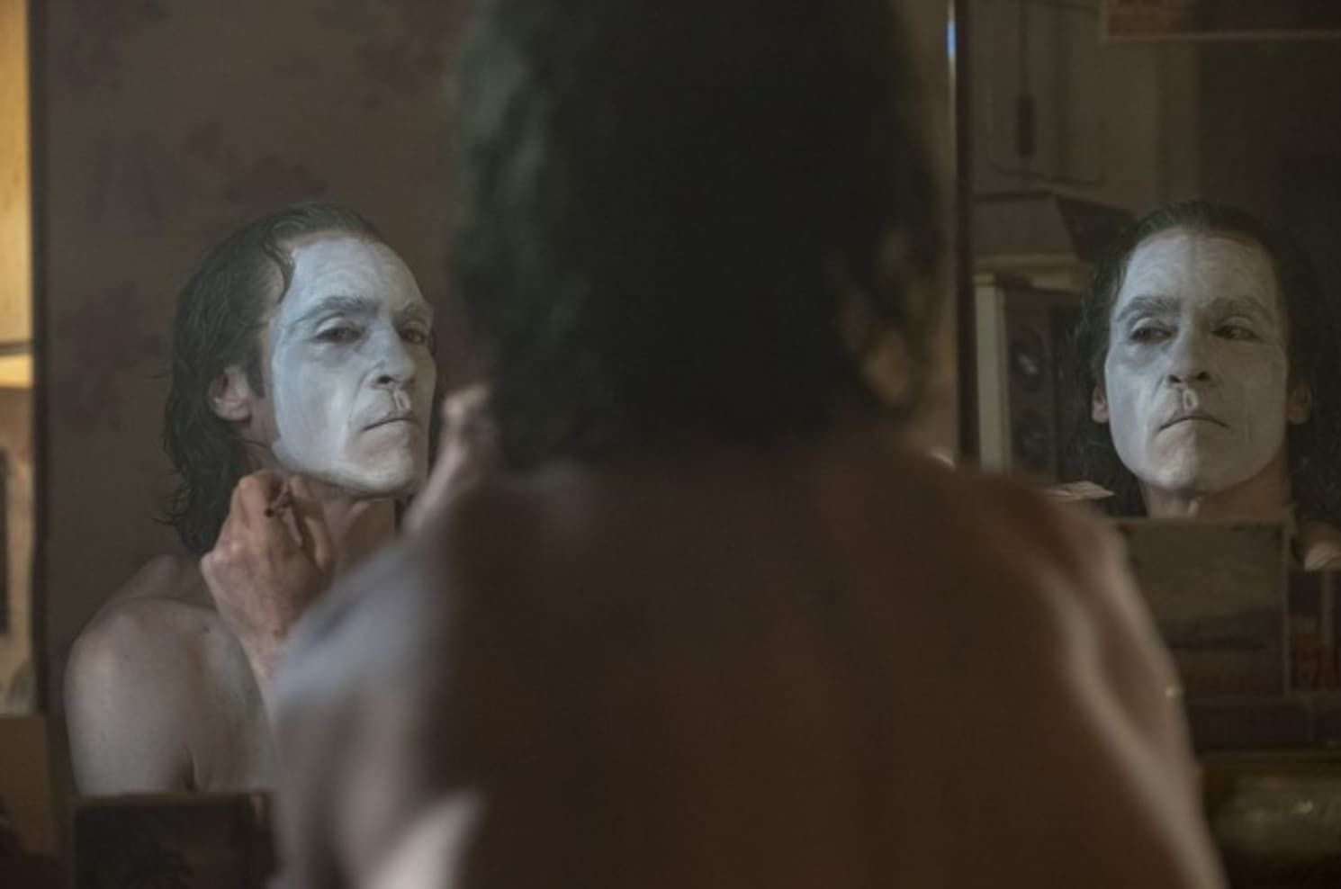 Green-skinned witch in a black hat and robe, looking concerned, next to a man in a green military-style jacket.