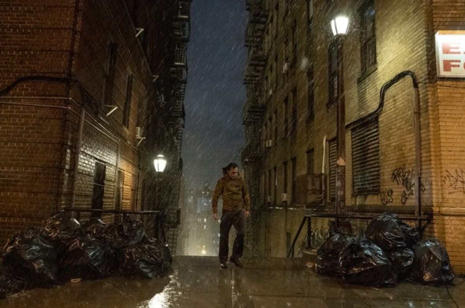 Michael Douglas in a convertible car, wearing sunglasses and a suit, looking to the side.