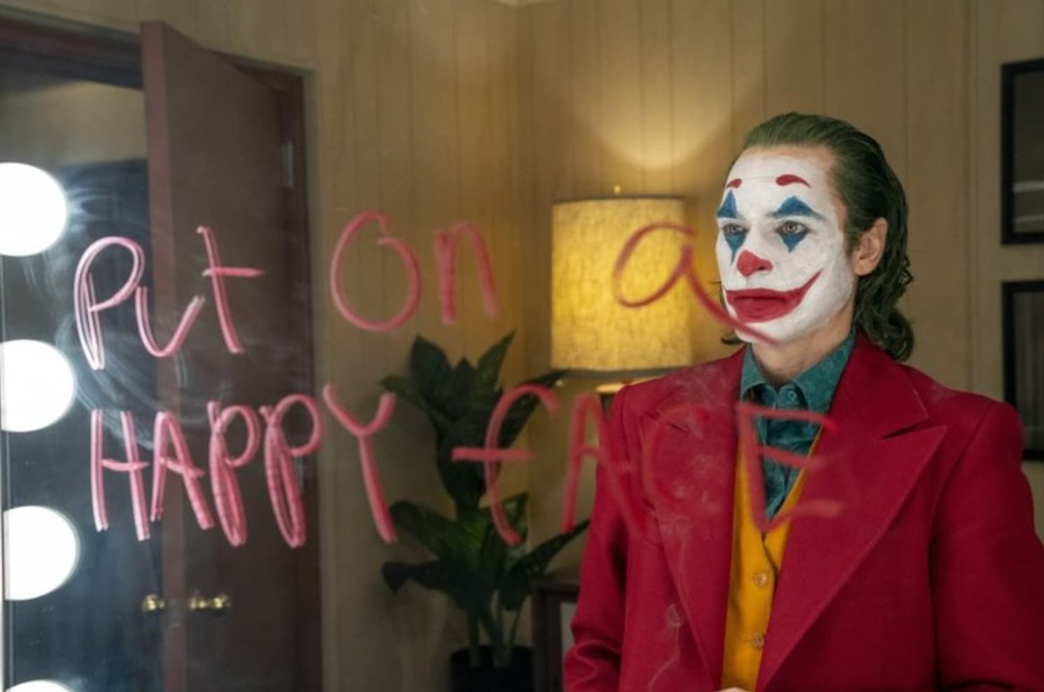 Arthur Fleck, as the Joker, stands before a mirror with 