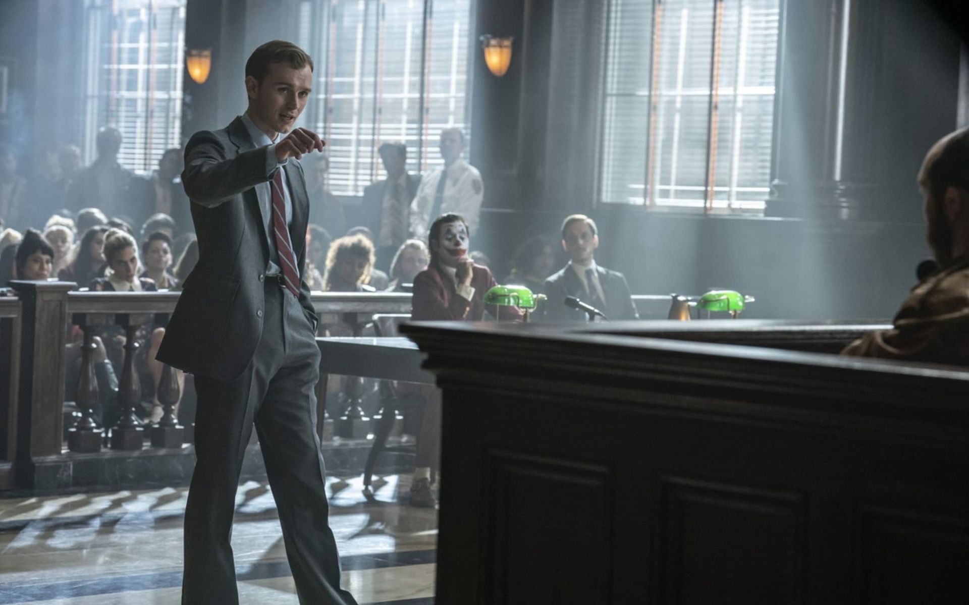 Michael Douglas in a convertible car, wearing sunglasses and a suit, looking to the side.