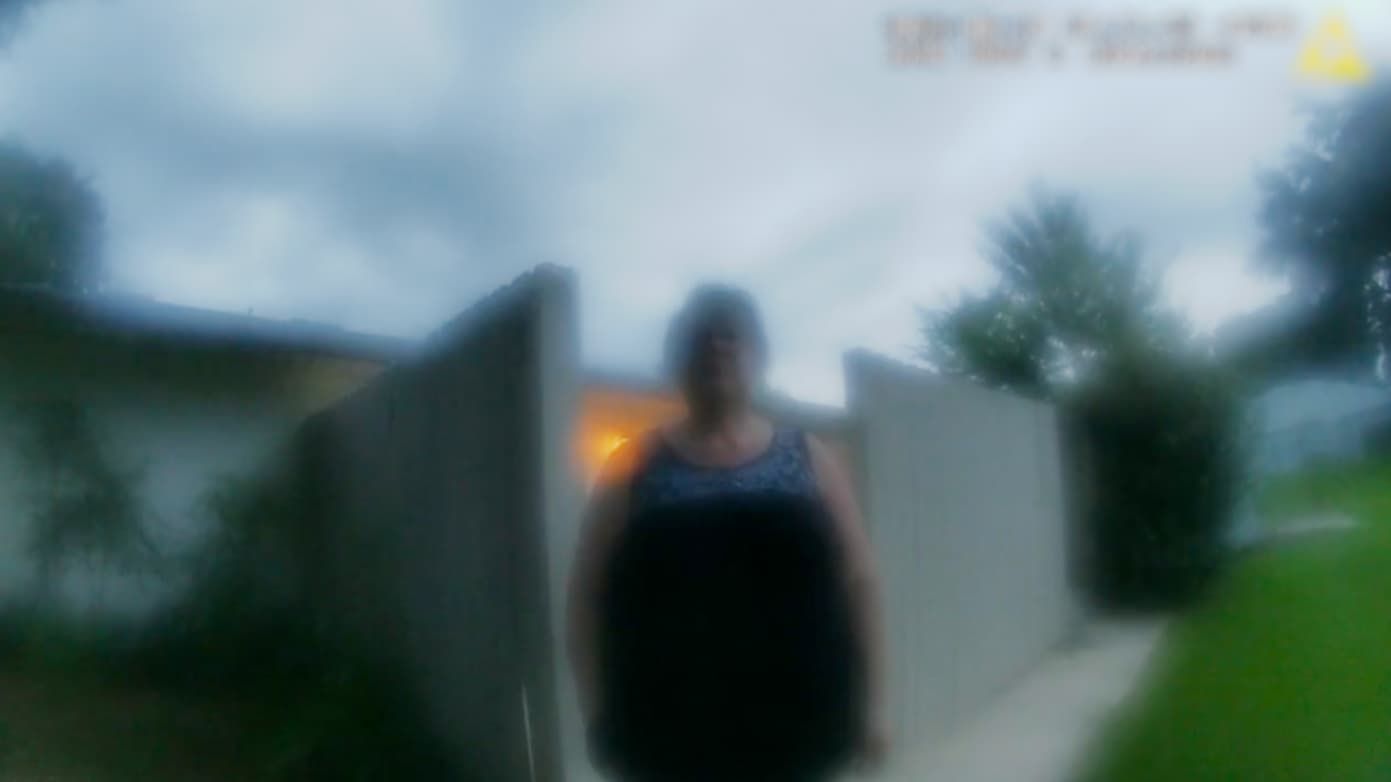 Blurred image of a person standing between two walls, outside on a cloudy day.