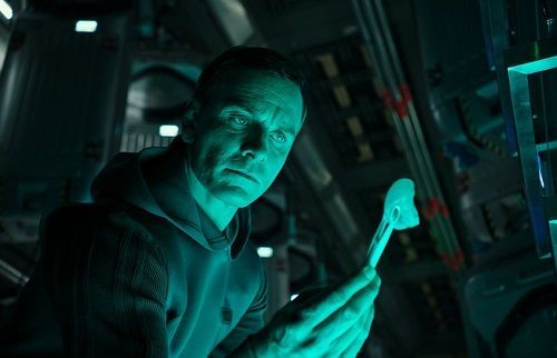 Michael Fassbender as the android David, holding a biological sample in a blue-lit spaceship.
