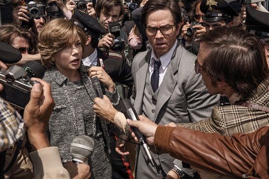A woman and man are surrounded by reporters with microphones. They look concerned, in an outdoor setting.