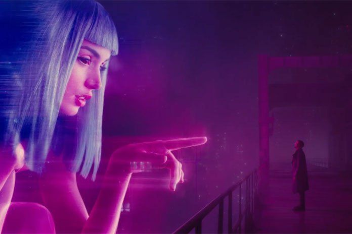 A holographic woman with blue hair points towards a man in a dark, neon-lit hallway.