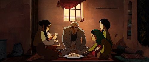 A family of four, sitting around a meal, in a warmly lit room.