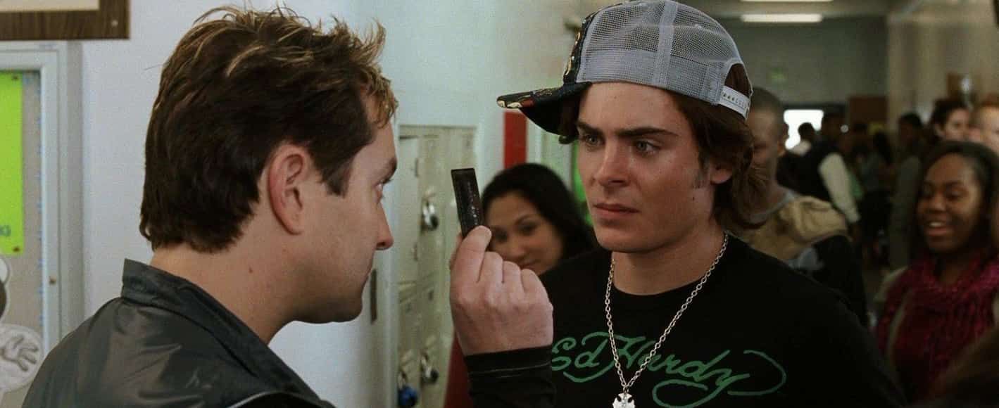 Two men in a school hallway face each other.