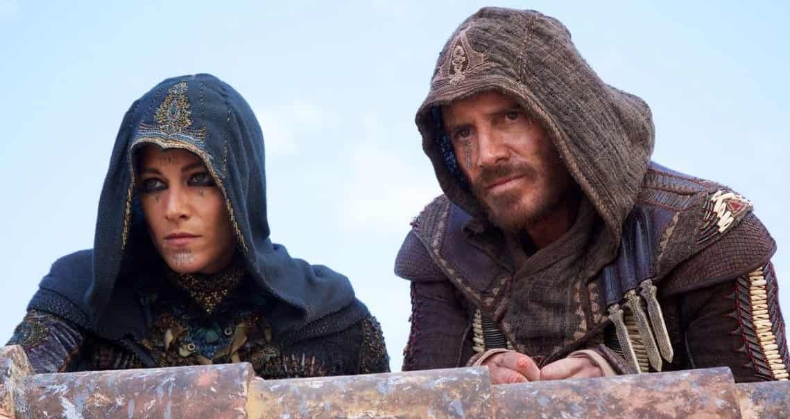 Two hooded figures looking out; woman left, man right. Both wear ornate robes, looking serious.