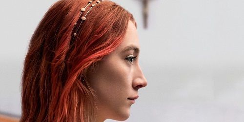 Close-up of a young woman with red hair wearing a beaded headband, gazing pensively to the side.