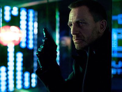 Daniel Craig as James Bond, holding a gun, in a dimly lit, high-tech setting with blue and green lights.