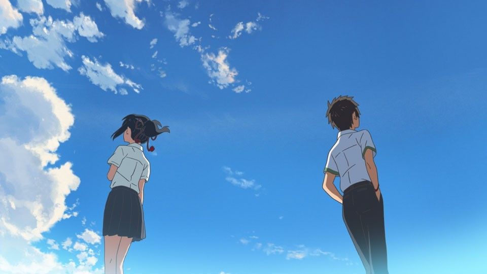 Two anime characters looking up at a bright blue sky with fluffy clouds.