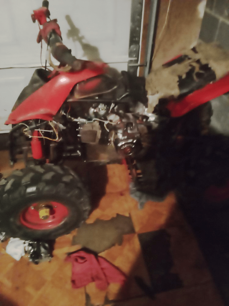 Red ATV with black tires and red rims, in a garage.