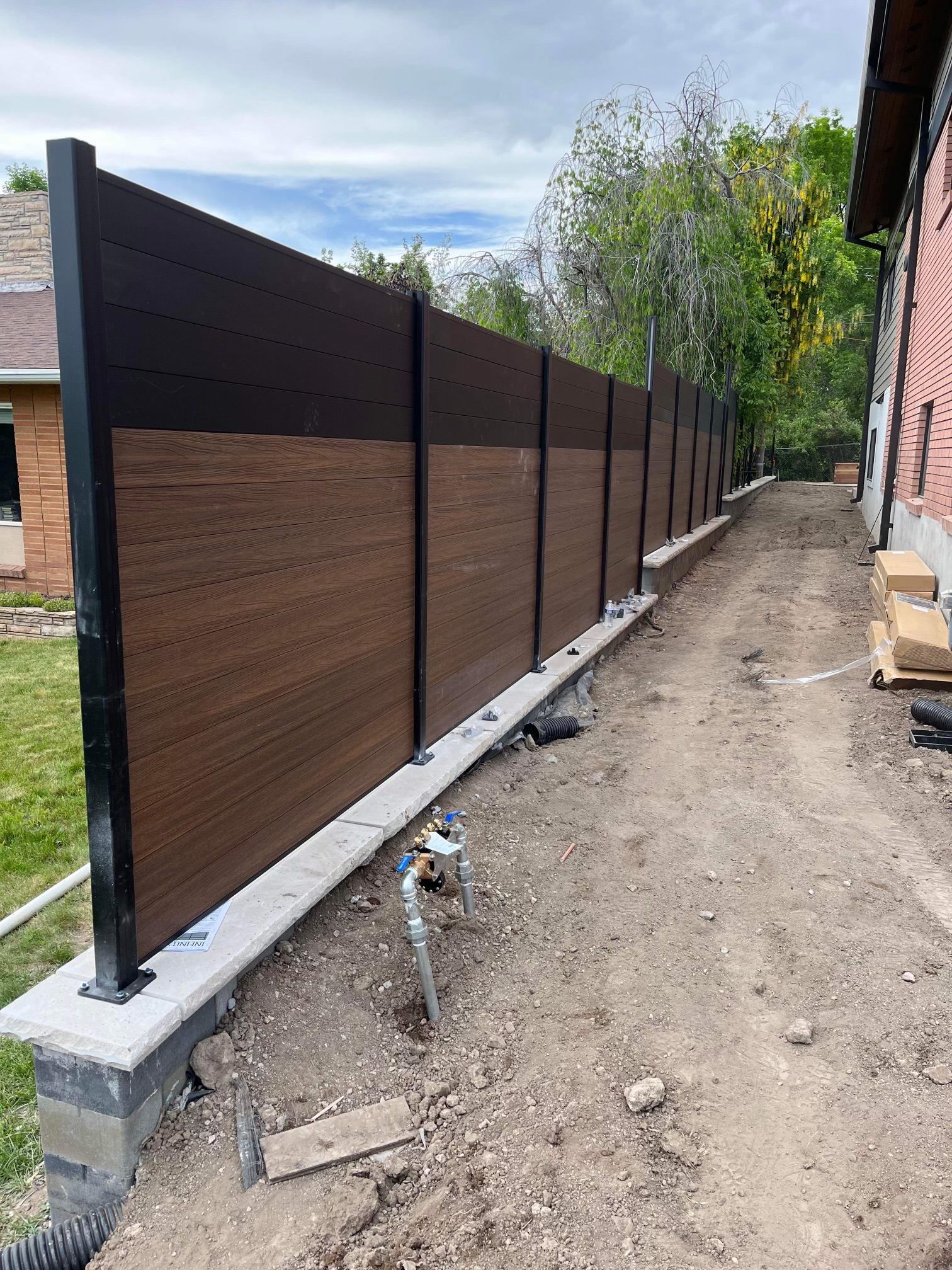 A black metal fence surrounded by green bushes and trees.