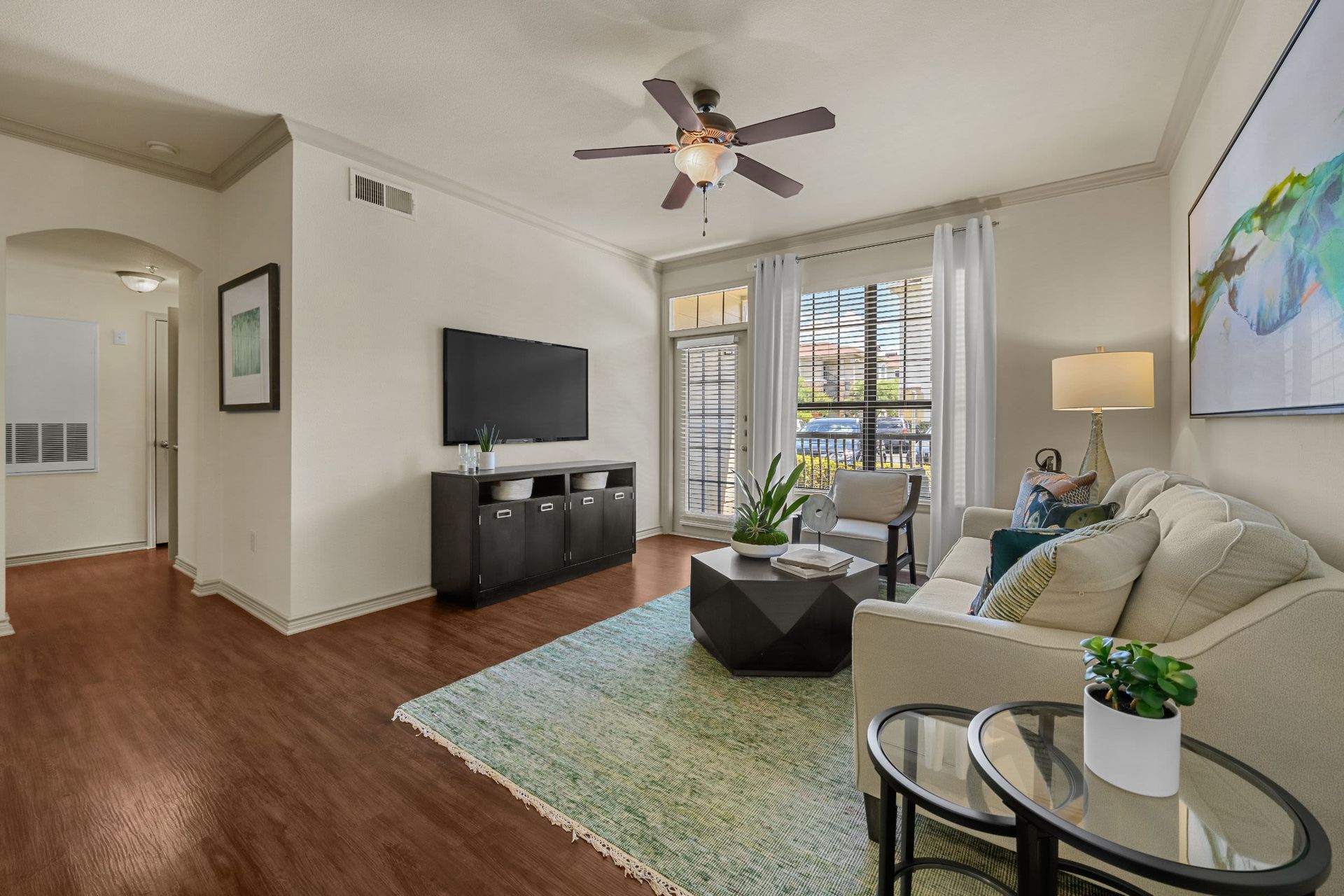 A living room with a couch, table, television, and ceiling fan at Marquis Lakeline Station in Austin, TX.
