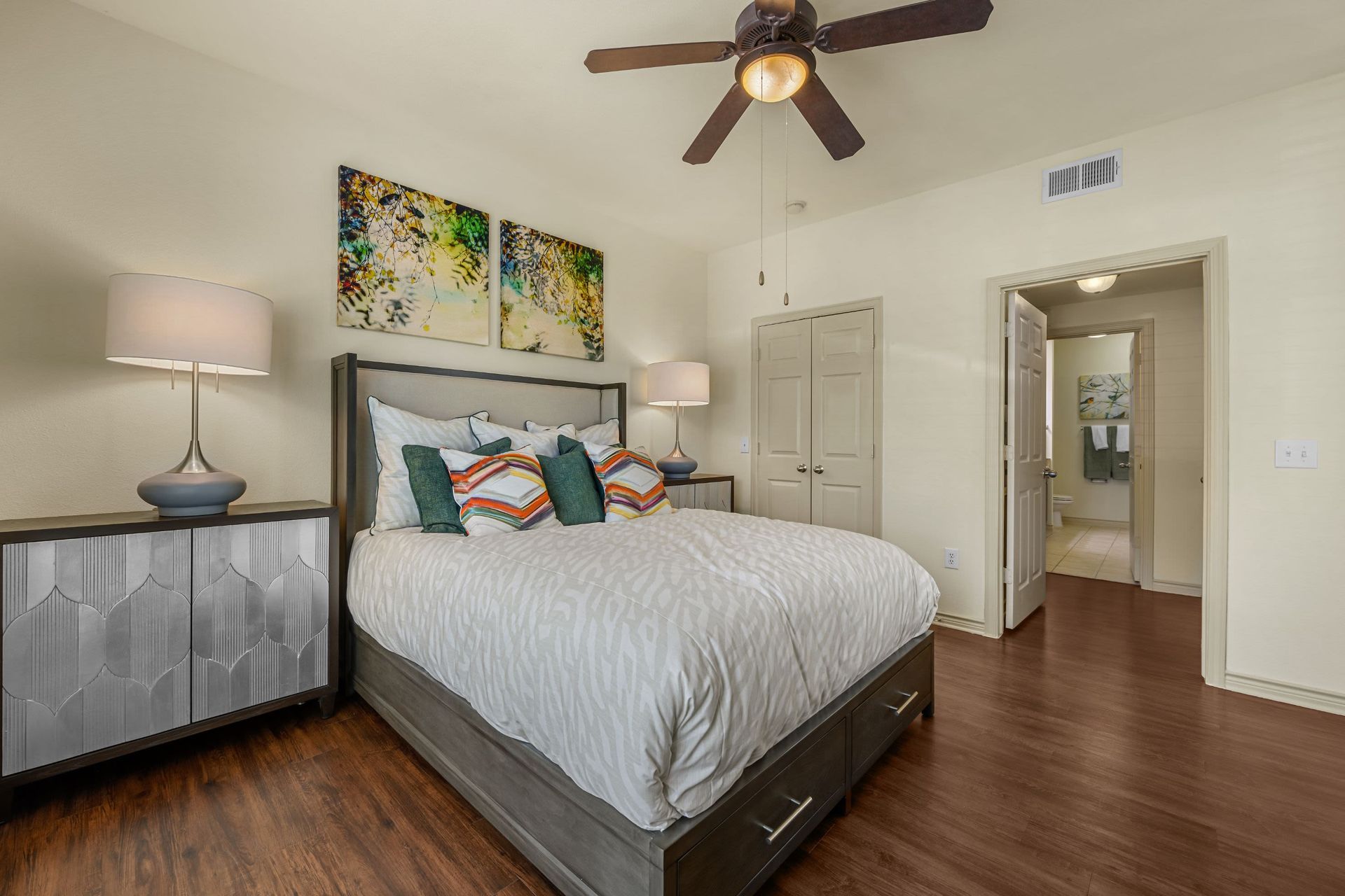 A bedroom with a bed, nightstand, lamps, and a ceiling fan at Marquis Lakeline Station in Austin, TX.