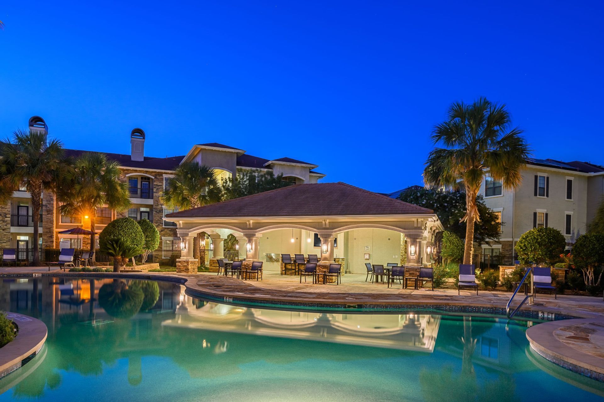 A large swimming pool in front of a building at night at Marquis Lakeline Station in Austin, TX.