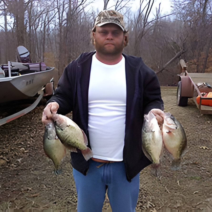 Man holding several fish outdoors beside a boat in a wooded area