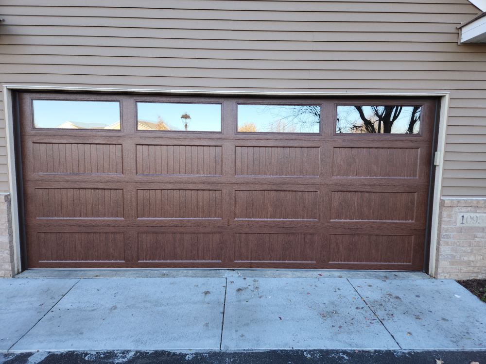 A brown garage door is sitting on the side of a house.