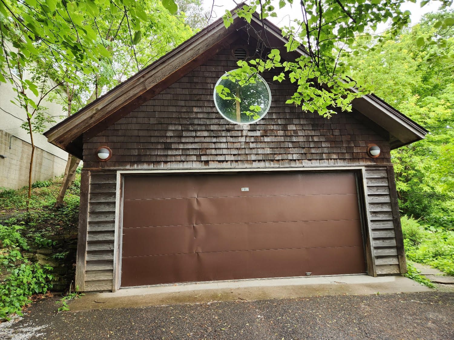 A garage with a brown door and a mirror on the side of it.