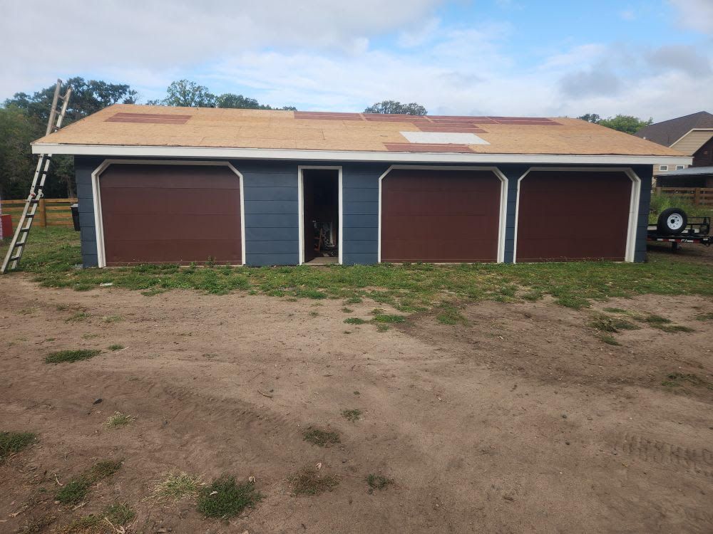 A garage with three garage doors and a ladder in front of it
