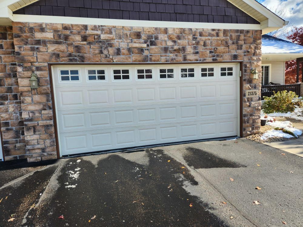A white garage door is sitting in front of a brick building.
