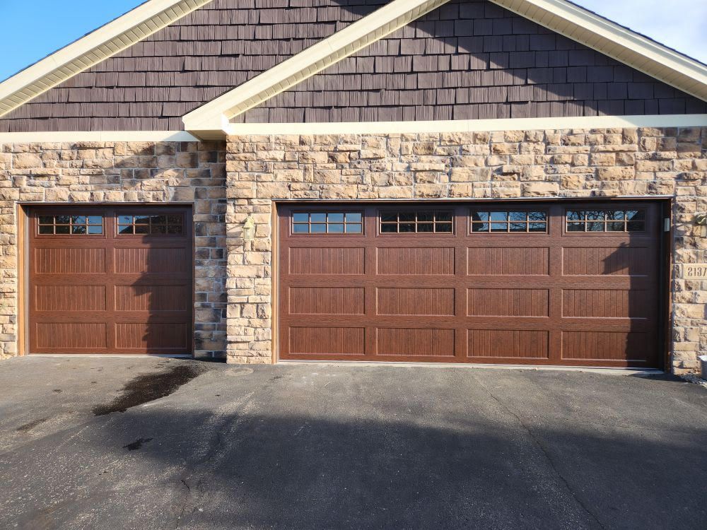 A house with two garage doors and a brick wall