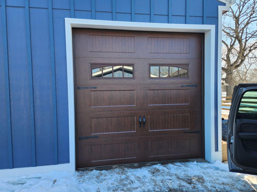 A car is parked in front of a garage door.