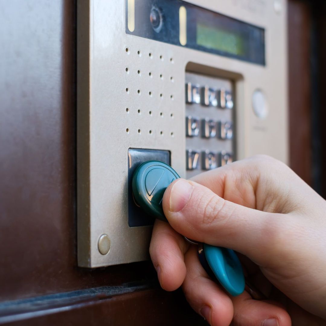 A staff member holding a key fob to the access control panel. 