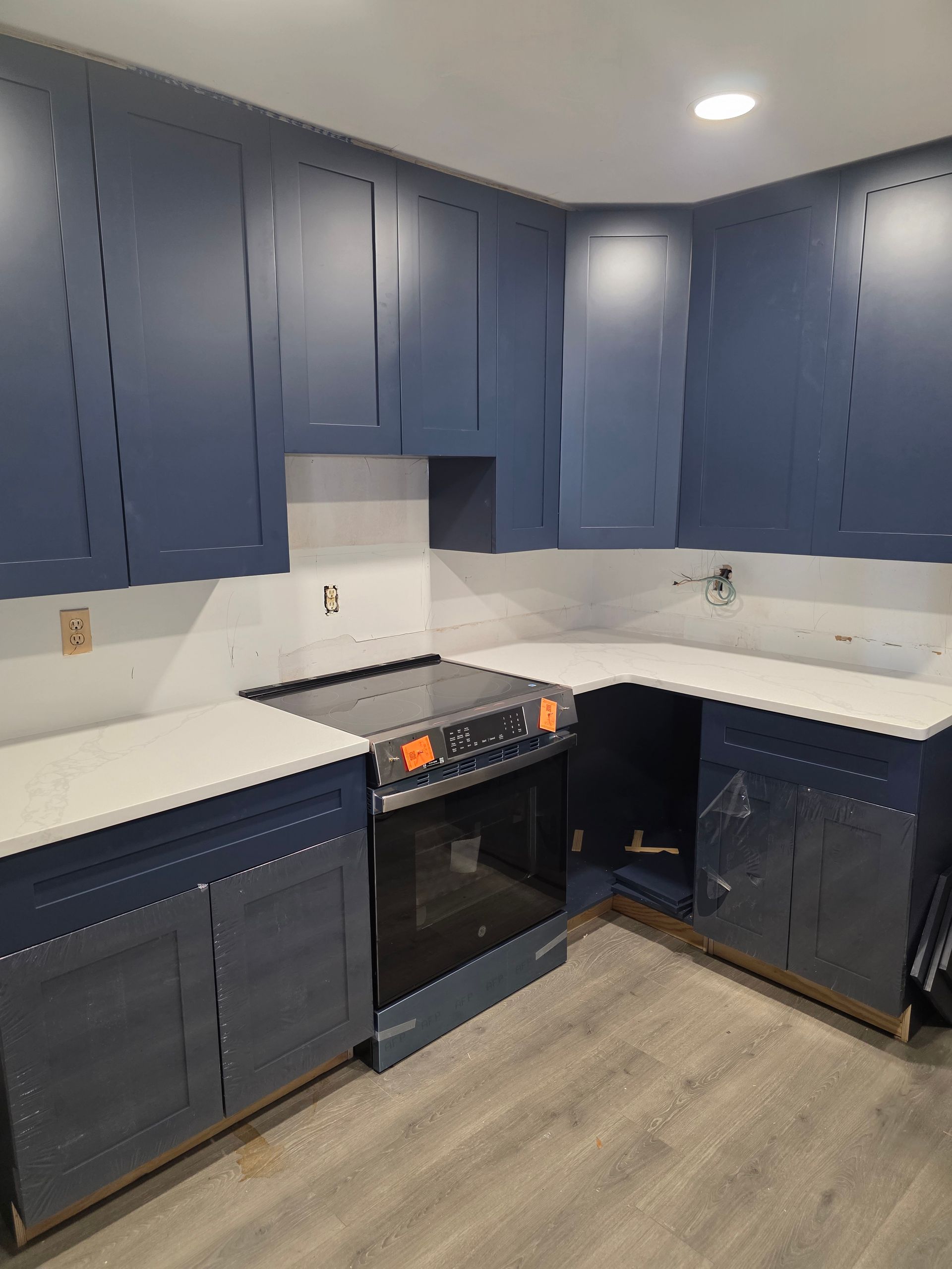 Blue kitchen cabinets and white countertops in a corner kitchen setting.
