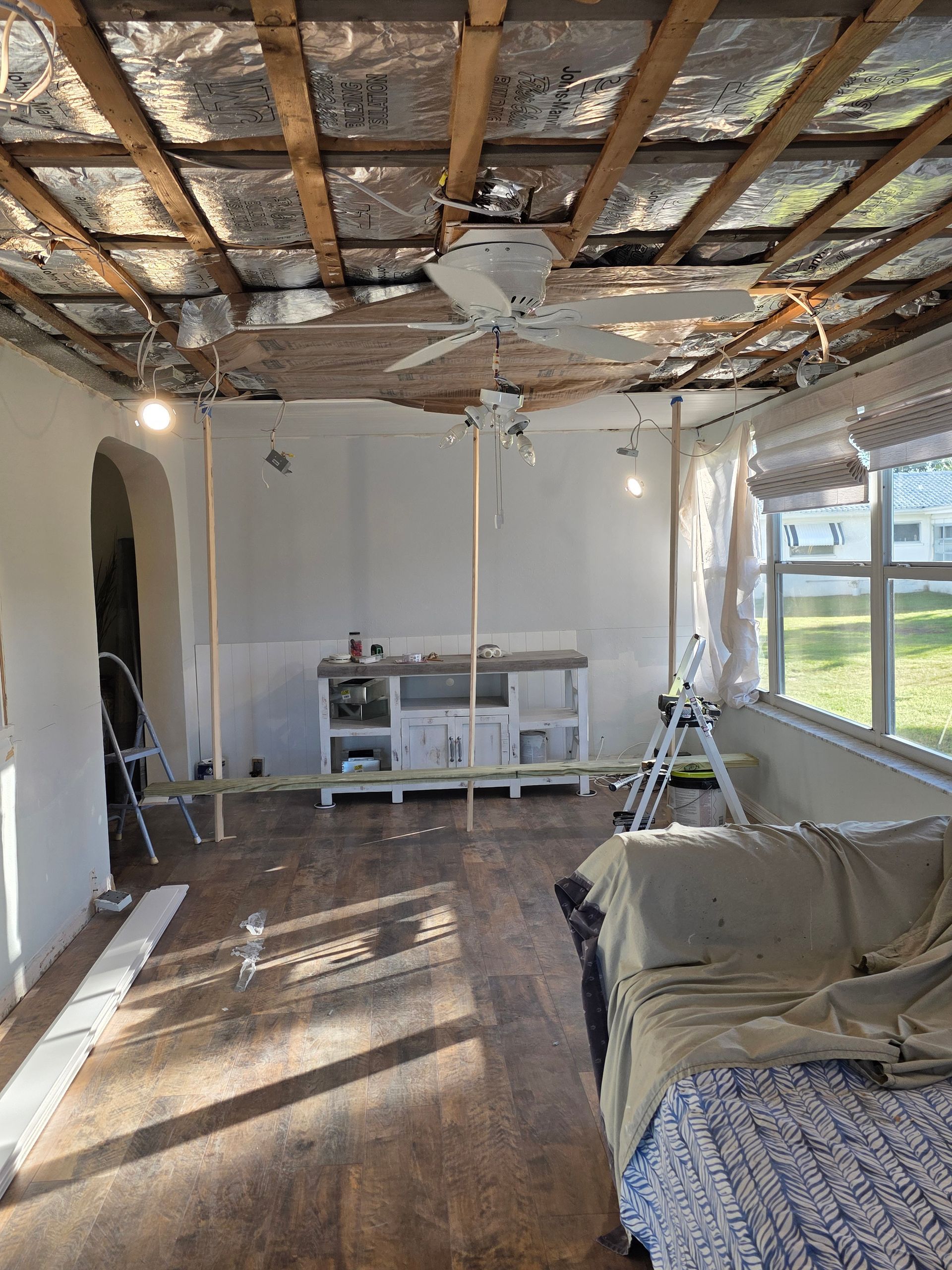 Man installing an electrical outlet in a kitchen, wearing a cap and gloves.